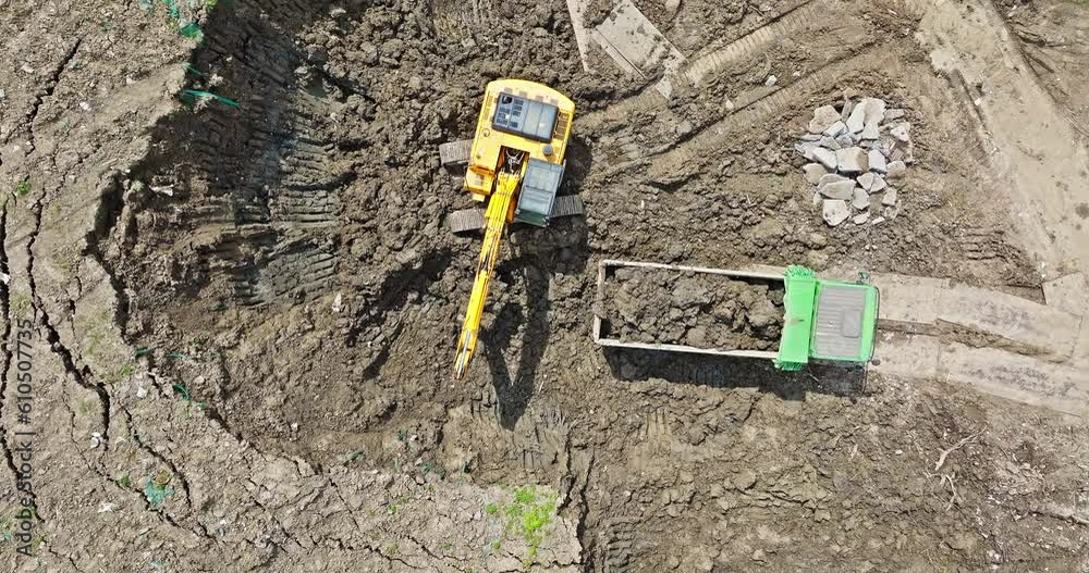 Aerial view of excavator equipment at the construction site. The excavator digs earthwork at the construction site. Aerial view of excavator equipment at the construction site. The excavator digs earthwork at the construction site.