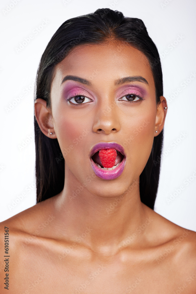 Woman, makeup and raspberry in mouth for studio portrait, glow color and skincare by white background. Face of indian model eating fruits with bold cosmetics, facial aesthetic and shine for beauty Woman, makeup and raspberry in mouth for studio portrait, glow color and skincare by white background. Face of indian model eating fruits with bold cosmetics, facial aesthetic and shine for beauty
