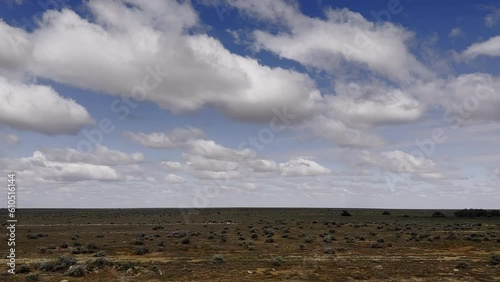 View from Indian Pacific of Nullabor treeless plain of Western Australia. Vast expanse zooms past beneath sky full of patchy clouds photo