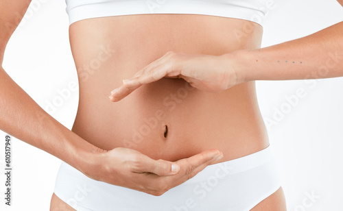 Stomach, wellness and hands of woman in studio for digestion, gut or health on white background. Abdomen, detox and lady person with finger shape for healthy, balance or weight loss, control or diet © Micah C/peopleimages.com