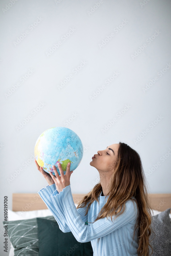 Fototapeta premium Happy woman with a globe in the living room.