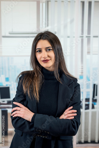 Portrait of a pretty happy young woman wear black suit stand alone in the office