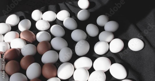 A large number of eggs, on a black background in the light of the sun