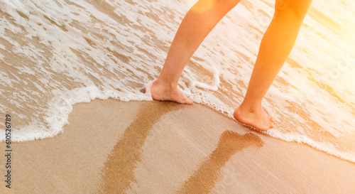 Woman walking on golden sand beach leaving footprints in the sand. Summer beach travel concept.