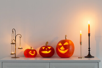  halloween pumpkins with burning candles in white interior