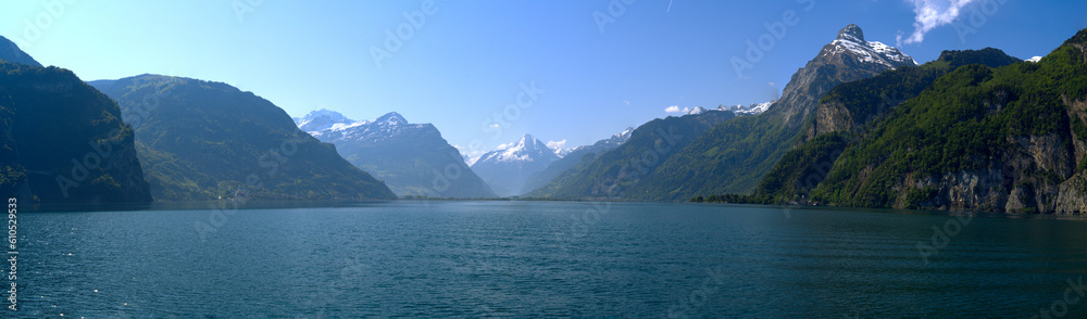 Scenic wide angle view of Swiss Alps with Lake Lucerne and Swiss village of Flüelen in the background on a sunny spring morning. Photo taken May 22nd, 2023, Flüelen, Canton Uri, Switzerland.