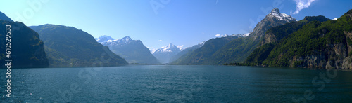 Scenic wide angle view of Swiss Alps with Lake Lucerne and Swiss village of Flüelen in the background on a sunny spring morning. Photo taken May 22nd, 2023, Flüelen, Canton Uri, Switzerland.