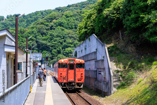 山陰本線餘部駅で電車を待つ乗客と入線するオレンジ色の電車 photo