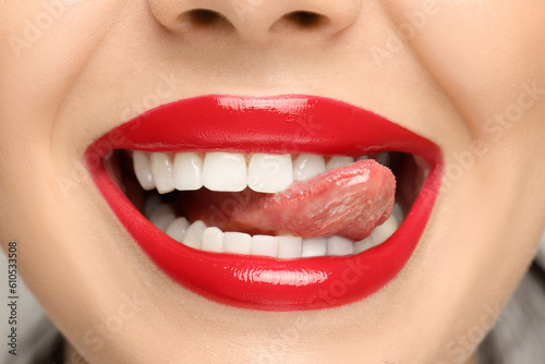 Woman with red lipstick showing her tongue, closeup