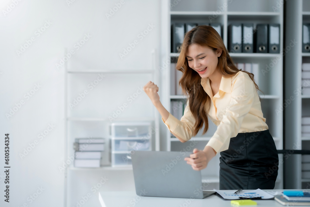 Happy businesswoman raising hands with victory smiling happily with laptop computer. The concept of success at work. Happy businesswoman raising hands with victory smiling happily with laptop computer. The concept of success at work.
