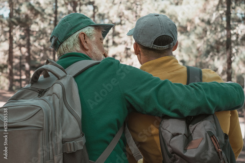 Back view of a couple of senior grandfather and young grandson together in a trekking day in the woods enjoying nature and healthy lifestyle. © luciano