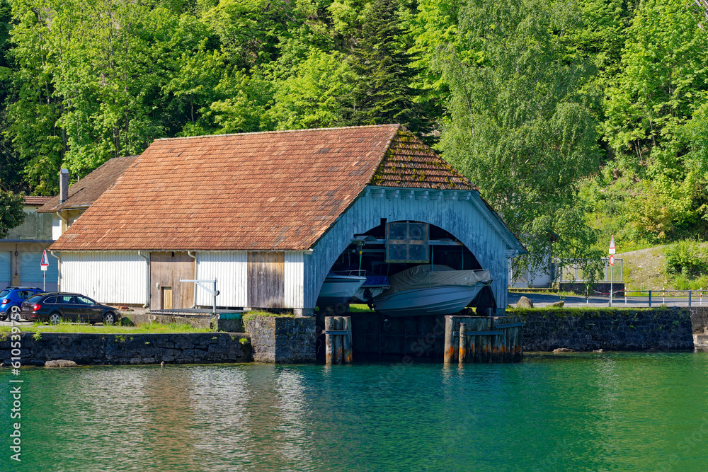 Scenic view boat house with Lake Lucerne in the foreground on a sunny spring day. Photo taken May 22nd, Isleten, Canton Uri, Switzerland. Scenic view boat house with Lake Lucerne in the foreground on a sunny spring day. Photo taken May 22nd, Isleten, Canton Uri, Switzerland.