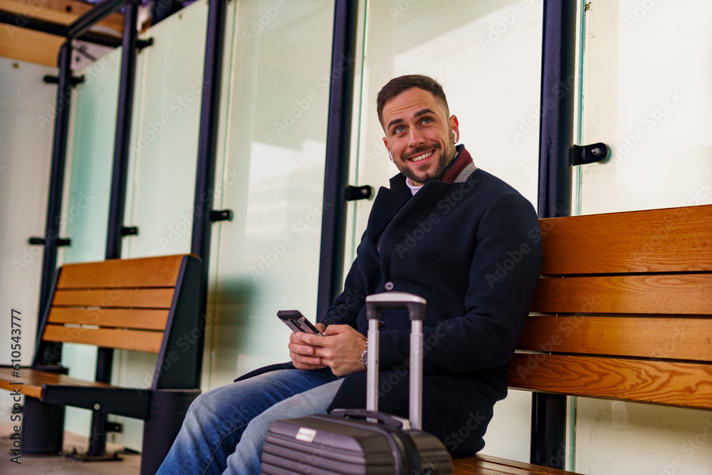 Business man sitting at the train or bus station waiting for his transportation, he's going on vocation Business man sitting at the train or bus station waiting for his transportation, he's going on vocation