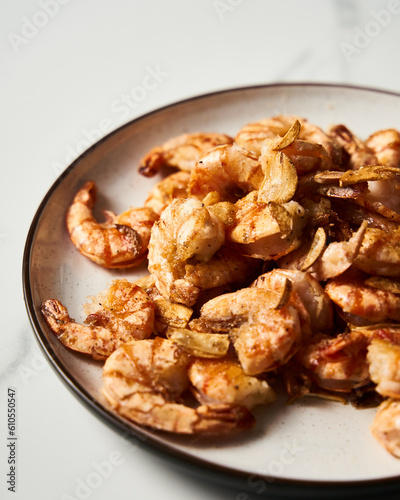 Crispy Pan fried tiger shrimps or prawns with garlic. Chinese or Asian cuisine dish. Shrimps lay on white plate on white marble background. T