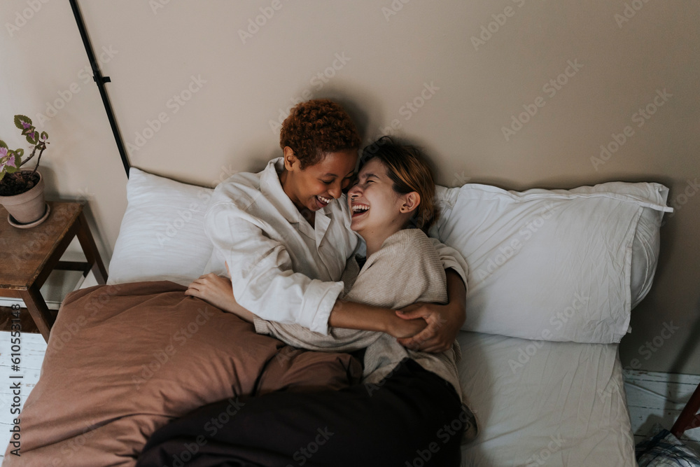 Non-binary couple enjoying with each other while lying on bed at home Non-binary couple enjoying with each other while lying on bed at home