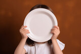 Cover Face with Empty Plate Child on Brown Background