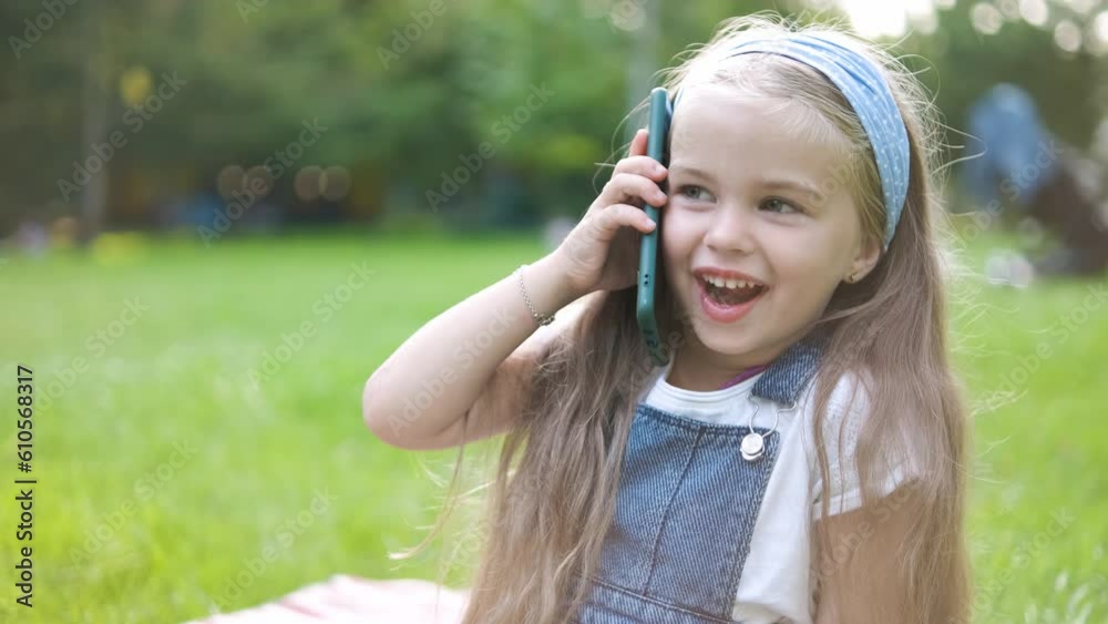 Happy child girl talking on mobile phone in summer park Happy child girl talking on mobile phone in summer park