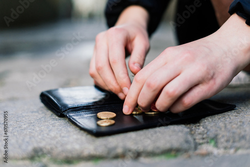 Female hands coins with wallet on paving stones street background