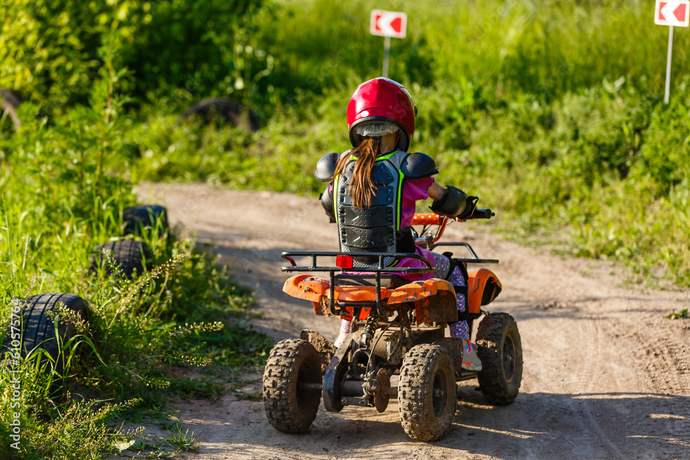 The little girl in protective clothing. Electric quad bike electric car for children popularizes green technology. The little girl in protective clothing. Electric quad bike electric car for children popularizes green technology.