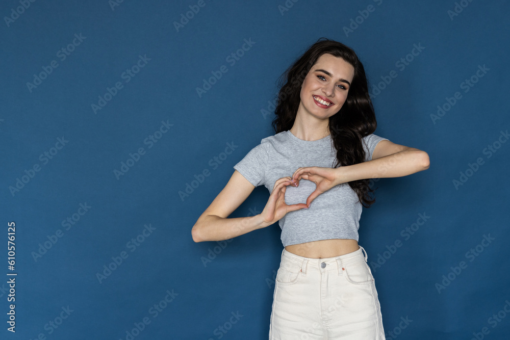Young beautiful woman over blue isolated background smiling in love doing heart symbol shape with hands. Young beautiful woman over blue isolated background smiling in love doing heart symbol shape with hands.