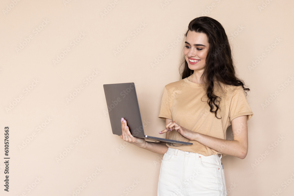 Portrait of gorgeous woman standing and holding laptop over beige background Portrait of gorgeous woman standing and holding laptop over beige background