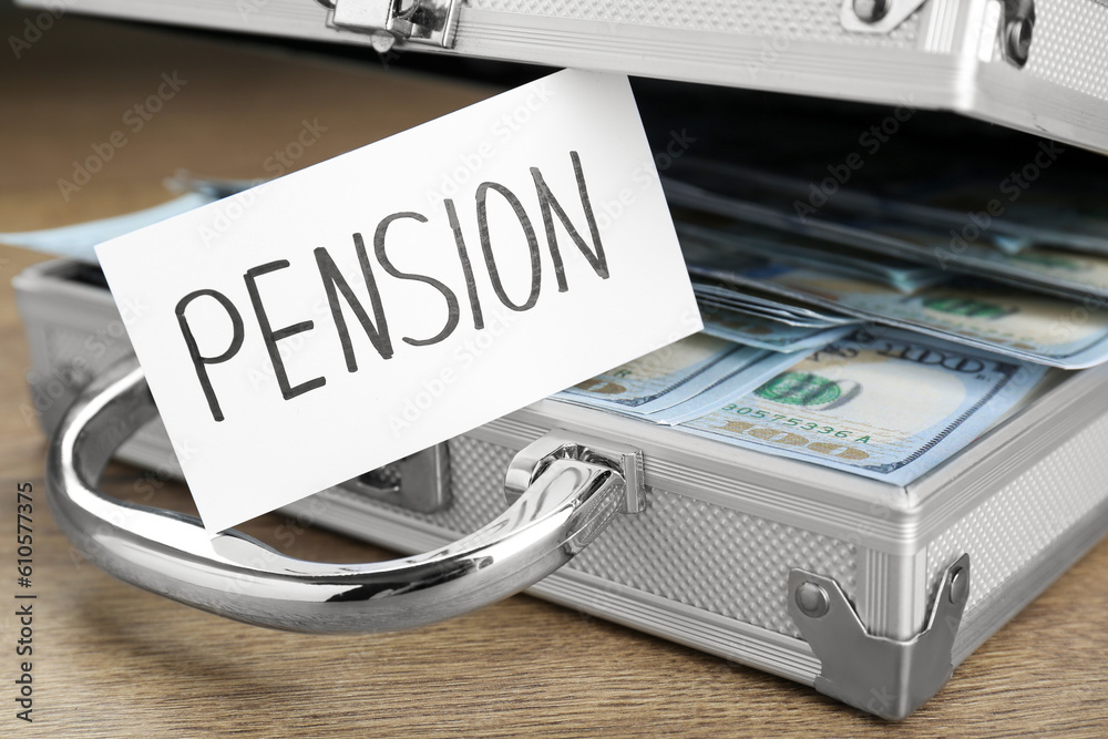 Card with word Pension and case of dollar banknotes on wooden table, closeup Card with word Pension and case of dollar banknotes on wooden table, closeup