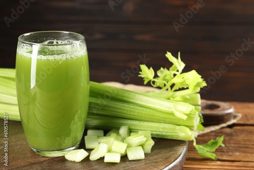 Glass of celery juice and fresh vegetables on wooden table, closeup