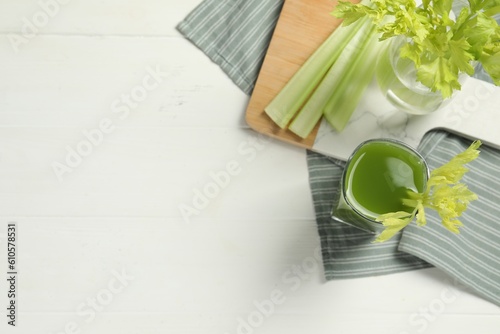 Glass of celery juice and fresh vegetables on white table, flat lay. Space for text