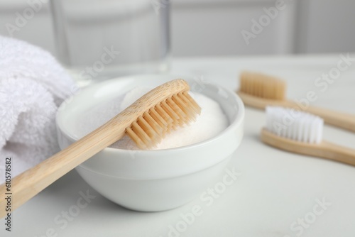 Bamboo toothbrushes  bowl of baking soda and towel on white table  closeup