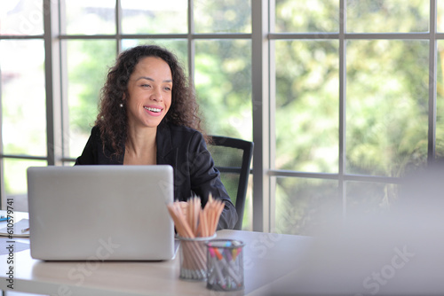 Attractive professional latin female employee worker sitting, using laptop computer with smart mobile phone at home workplace. Businesswoman working on paperwork while looking at camera and smile Free Download Attractive professional latin female employee worker sitting, using laptop computer with smart mobile phone at home workplace. Businesswoman working on paperwork while looking at camera and smile - GFXLoad