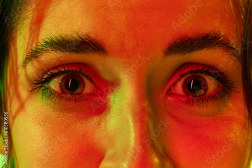 Quadro su tela Close up portrait of young charming female face with big eyes full of fear over studio background in neon light