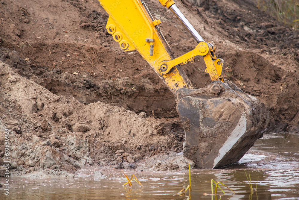 Close up of shovel of excavator digging artificial pond. Construction work in countryside Close up of shovel of excavator digging artificial pond. Construction work in countryside