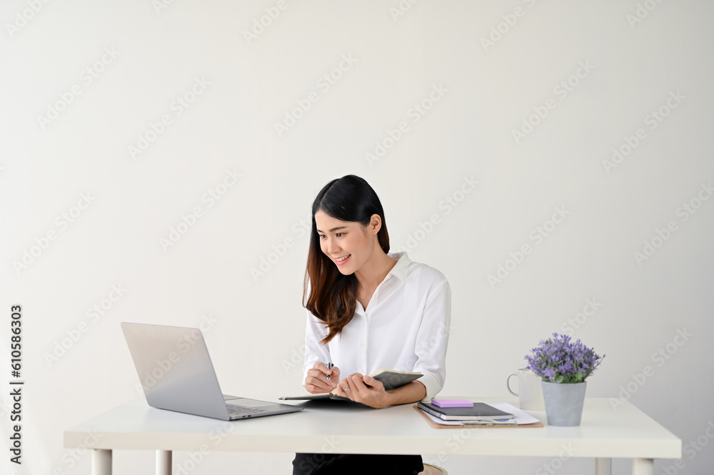 A businesswoman looking at her laptop screen and working on her tasks at her desk A businesswoman looking at her laptop screen and working on her tasks at her desk