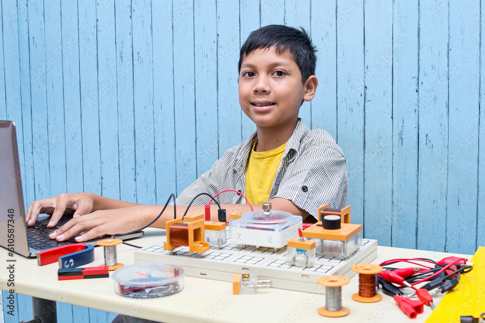 Smart looking Asian boy working with circuits, wires, computer, motor on his project. Science, Technology, Engineering and Mathematics (STEM) education concept. Smart looking Asian boy working with circuits, wires, computer, motor on his project. Science, Technology, Engineering and Mathematics (STEM) education concept.