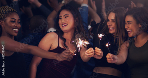 Sparkler, party and night with women in club for music, celebration and nightlife concert. Festival, disco and happy hour with friends dancing in crowd at social event for energy, techno and dj show
