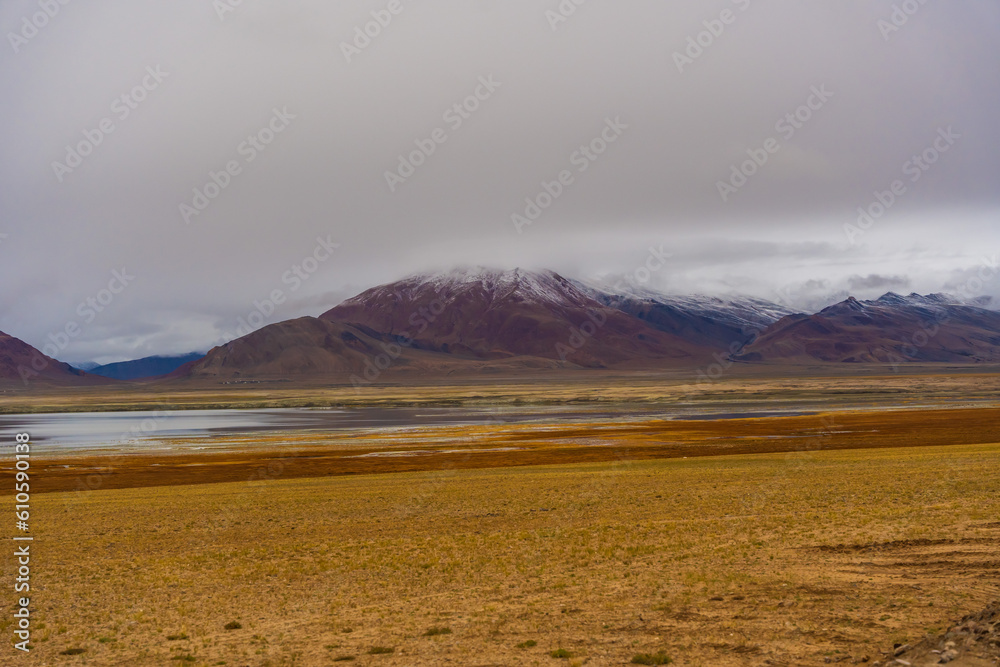 withered grass field, the mountain and cloud sky at Tso Kar lake, Beautiful scenery along the way at Ladakh, India. The Tso Kar or Tsho kar is a fluctuating salt lake