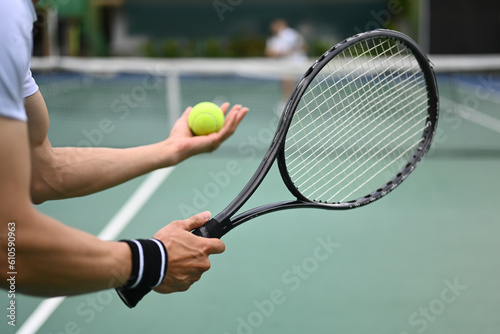 Cropped image of male tennis player with racket serving ball during match © Prathankarnpap