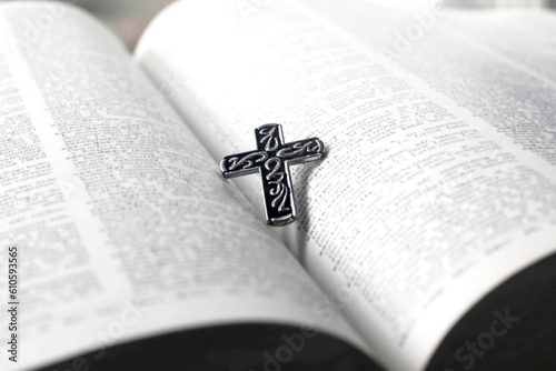 Closeup image of metal cross which places on opending bible book, soft focus, concept for religious lifestyle of christian people around the world.