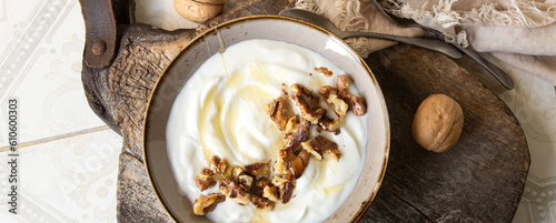 a bowl of greek yogurt with walnuts and honey on a light table