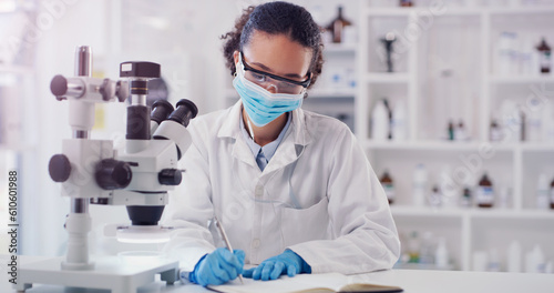 Scientist face mask, woman writing and lab worker with medical research in a clinic. Data work, planning and working of a young female employee with a notebook and microscope results for science