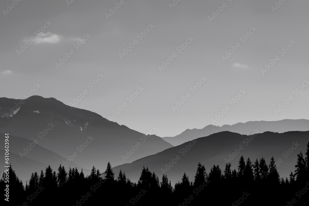Silhouettes of mountains with an orange color of sunset and sunrise. Forest silhouettes. Mountains landscape.