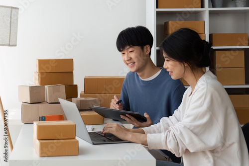 Happy couple people packing parcel boxes, couple lover checking order online on laptop at home