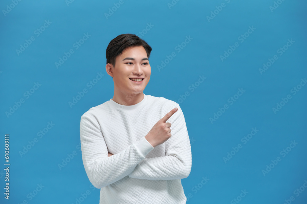 The young man standing on his side pointed his hand to the side with a cheerful expression The young man standing on his side pointed his hand to the side with a cheerful expression