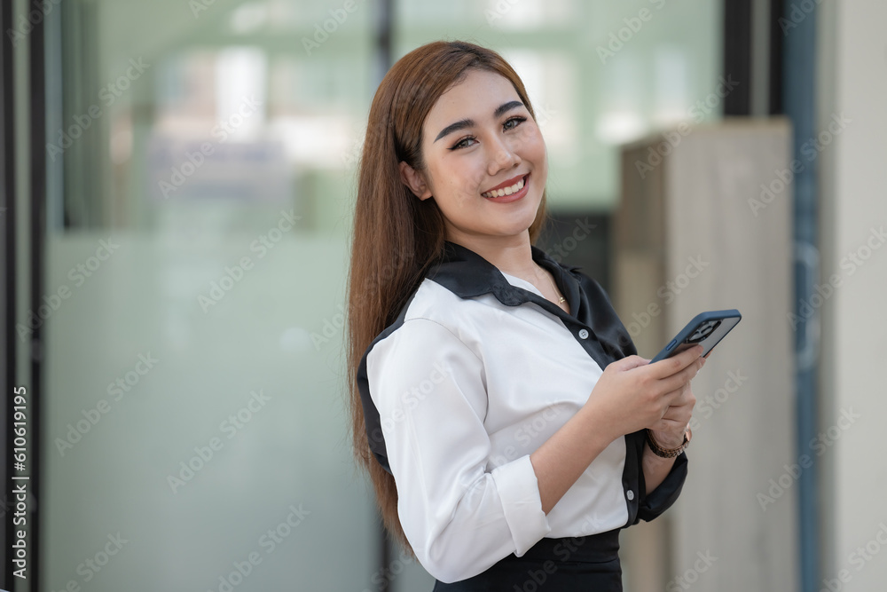 Asian businesswoman holding a mobile phone and looking at a camera. Asian businesswoman holding a mobile phone and looking at a camera.