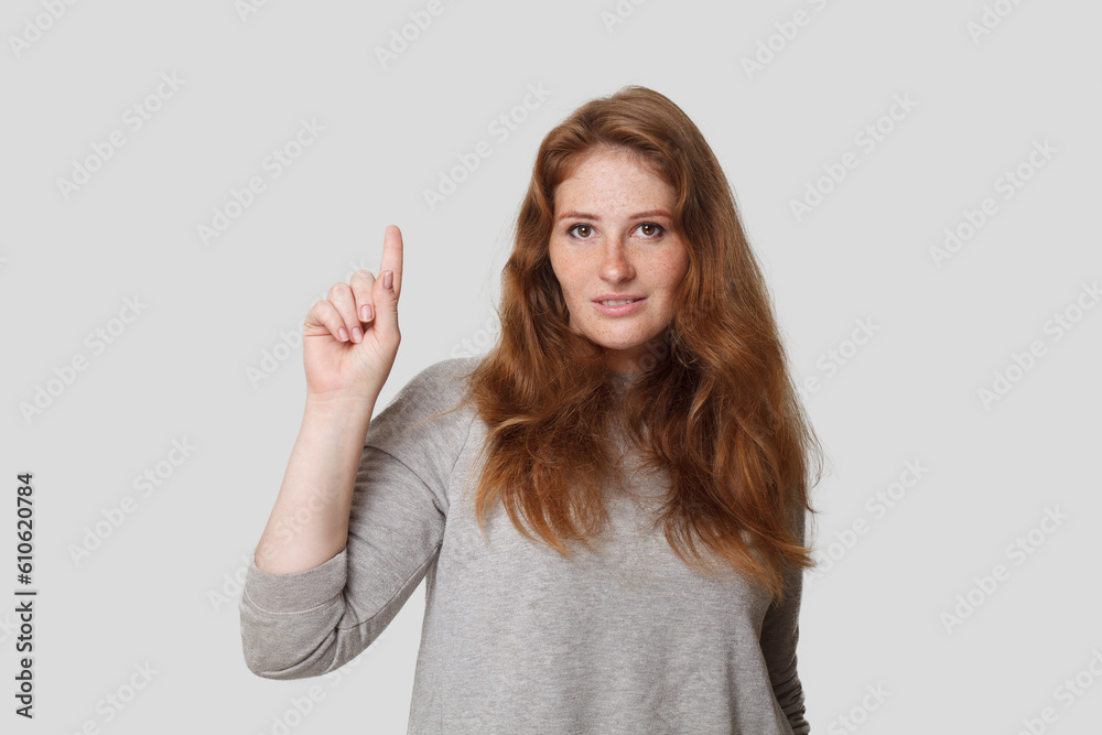 Cute smart woman pointing finger up on white background, studio portrait Cute smart woman pointing finger up on white background, studio portrait