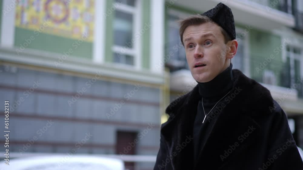 Portrait of young gay man waiting on city street looking away greeting waving. Smiling happy Caucasian LGBT person outdoors Portrait of young gay man waiting on city street looking away greeting waving. Smiling happy Caucasian LGBT person outdoors