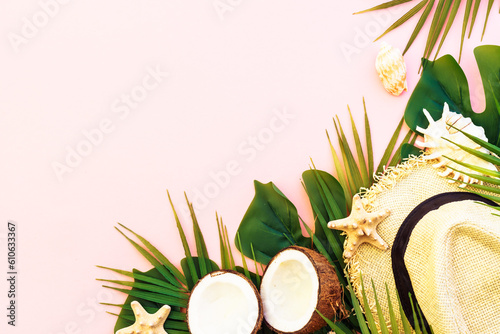 Summer flat lay background. Tropical leaves, coconut, hat and sea shells on pink background.
