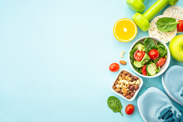Healthy lifestyle and diet food background. Sport shoes, dumbell and healthy food on blue. Flat lay with copy space.
