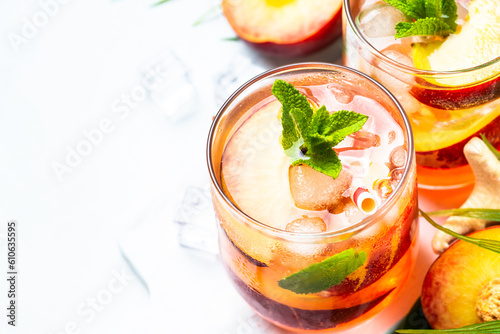 Peach cocktail, iced peach tea, fruit drink, summer beverage with fresh fruits, ice and mint. Close up.