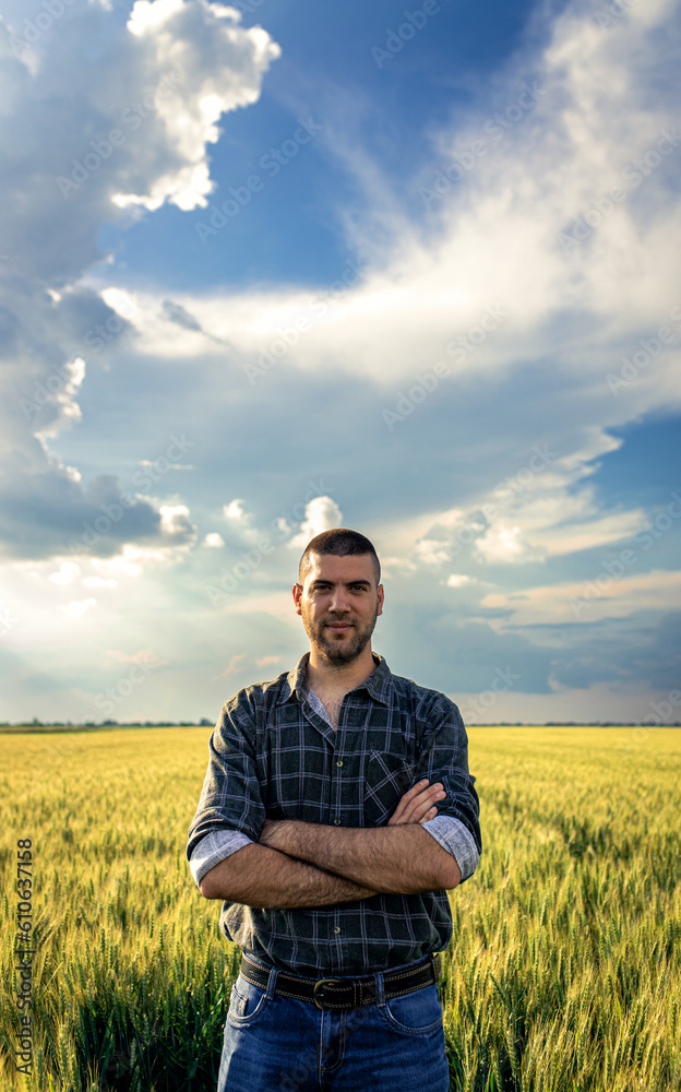 Portrait of young farmer standing in a green wheat field looking at camera. Portrait of young farmer standing in a green wheat field looking at camera.